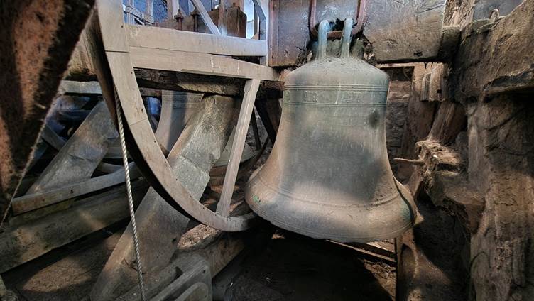 A large bell in a wooden wheel

AI-generated content may be incorrect.